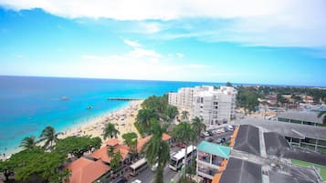 A coastal town with a beach, buildings, and a clear sky.