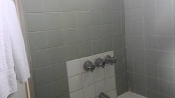 A bathroom with a bathtub, a towel rack, and a showerhead.