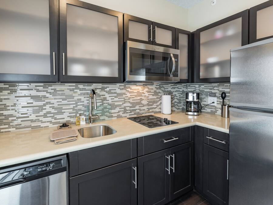 A modern kitchen with stainless steel appliances, a tiled backsplash, and dark cabinetry.