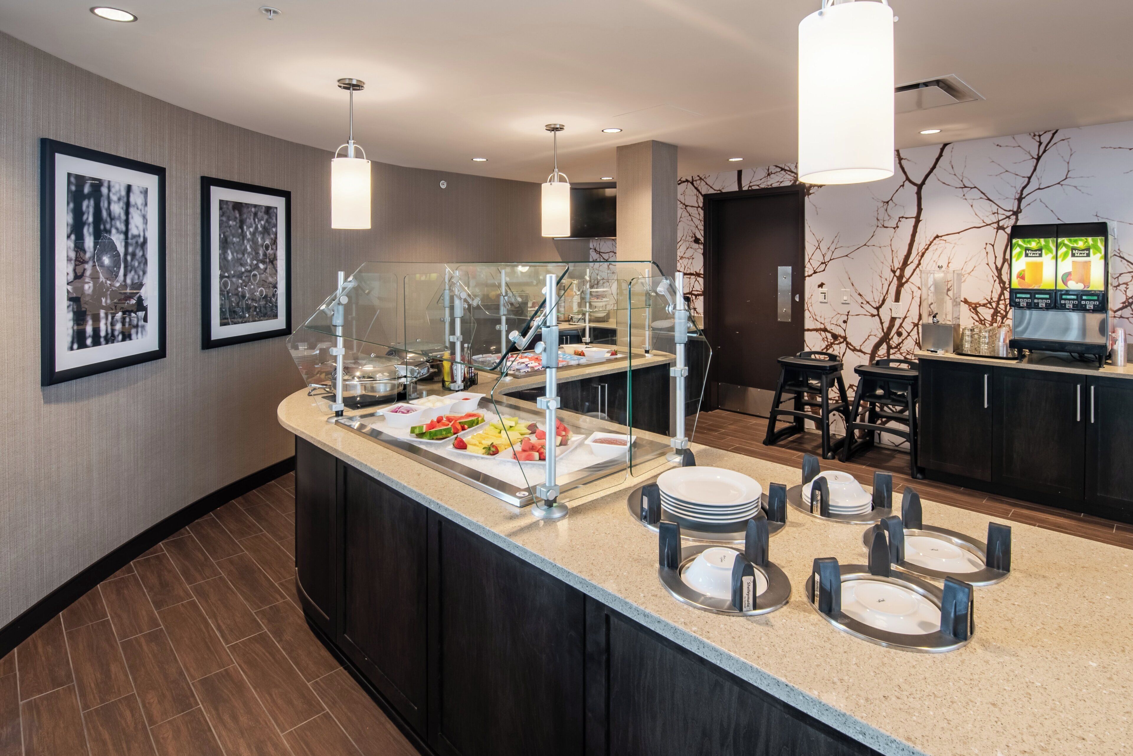 A hotel room with a breakfast bar, a fruit display, and a coffee machine.