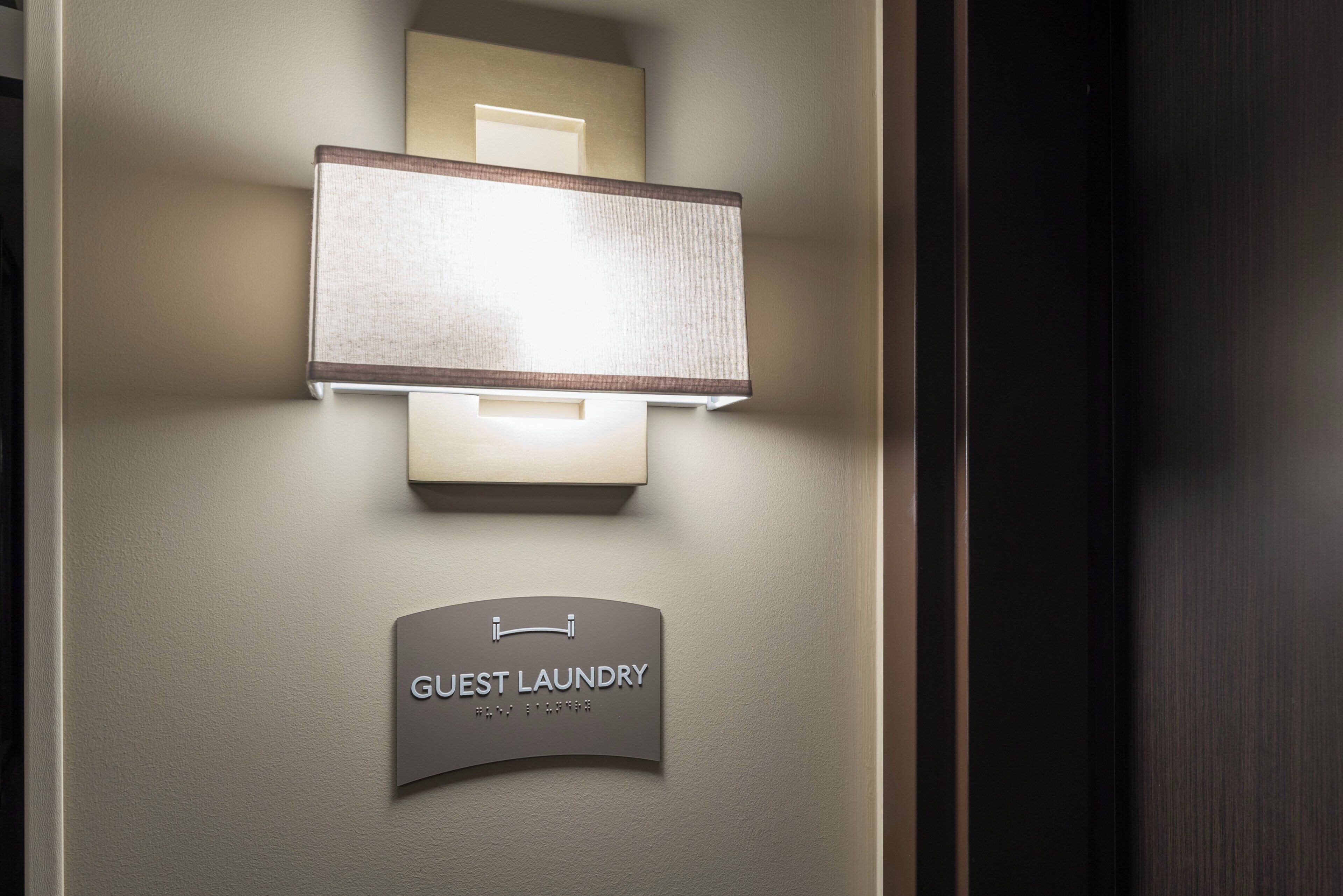 A wall-mounted light fixture with a sign below it reading 'GUEST LAUNDRY'.