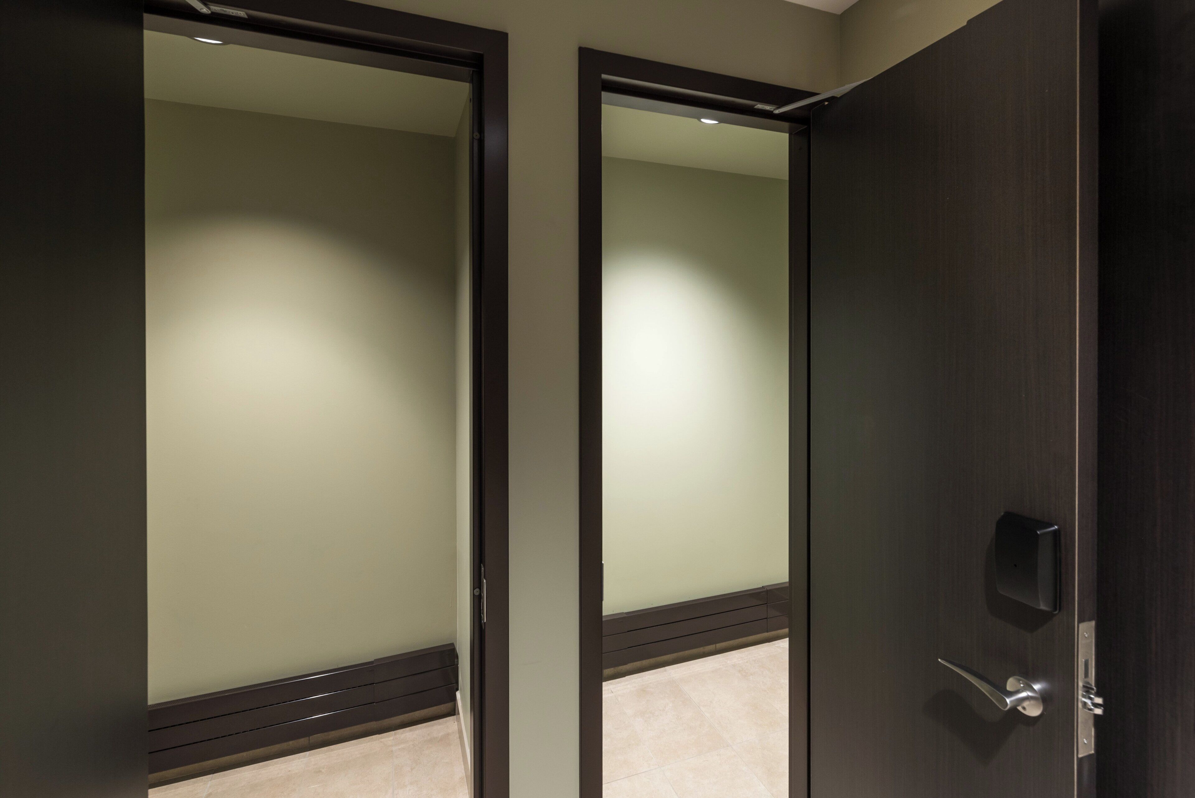 A closed door with a mirror reflecting a lighted room.