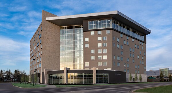 Un hôtel moderne à plusieurs étages, doté d’une façade en verre remarquable, d’un toit plat et d’un parking situé à l’avant.