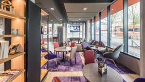 Un intérieur moderne avec des coins salon, une bibliothèque et de grandes fenêtres.
