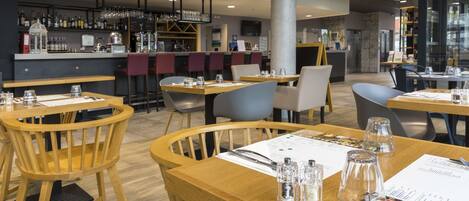 A restaurant with wooden tables and chairs, a bar area with bottles and glasses, and a menu on the tables.