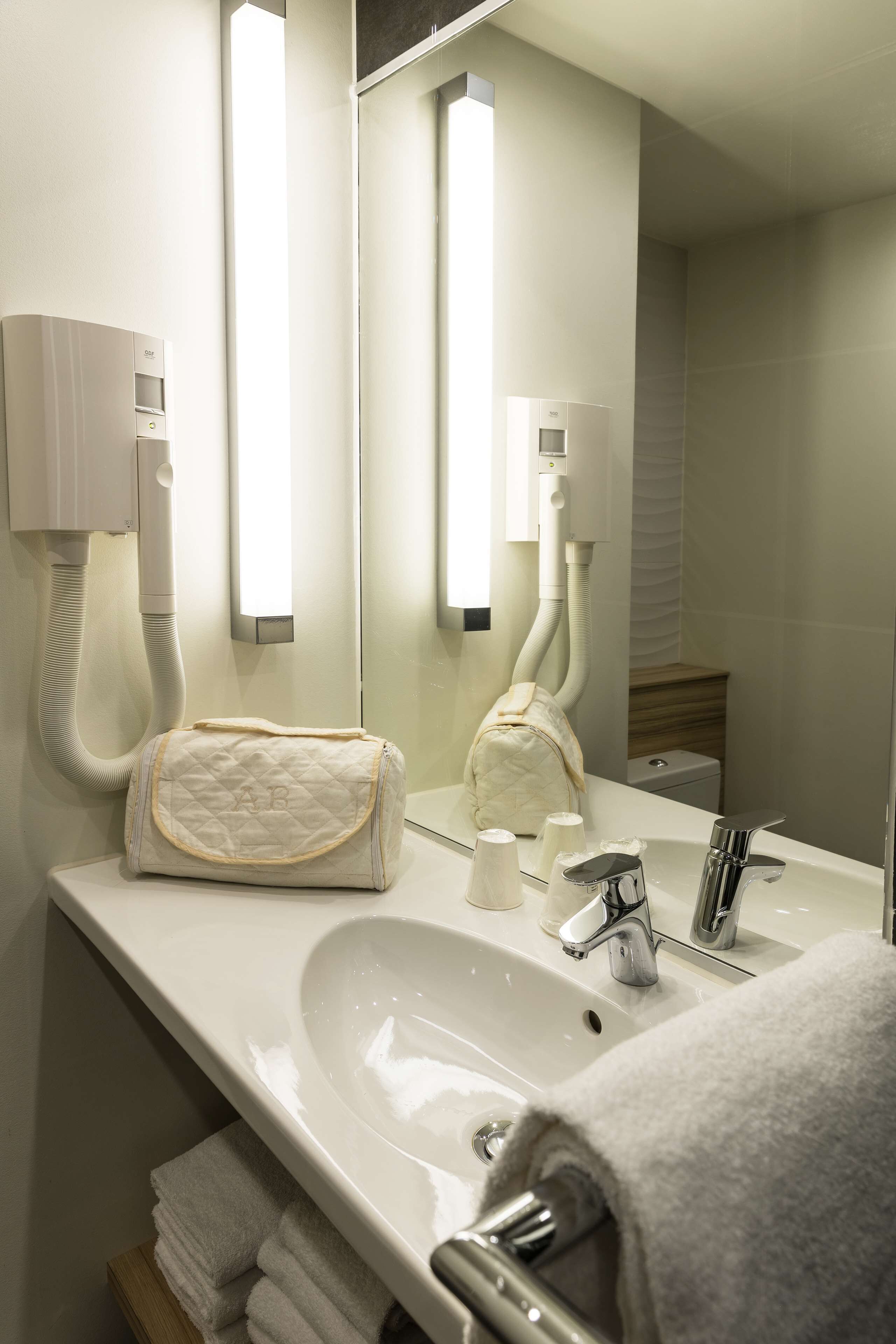 A bathroom with a sink, mirror, towel rack, and a hairdryer.