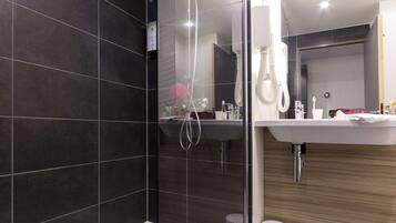 Une salle de bain moderne avec une douche à parois de verre, une baignoire blanche et un meuble-lavabo en bois doté d’un miroir.