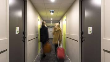 A hotel hallway with doors numbered 106 and 107, a carpeted floor, and a ceiling with recessed lighting.