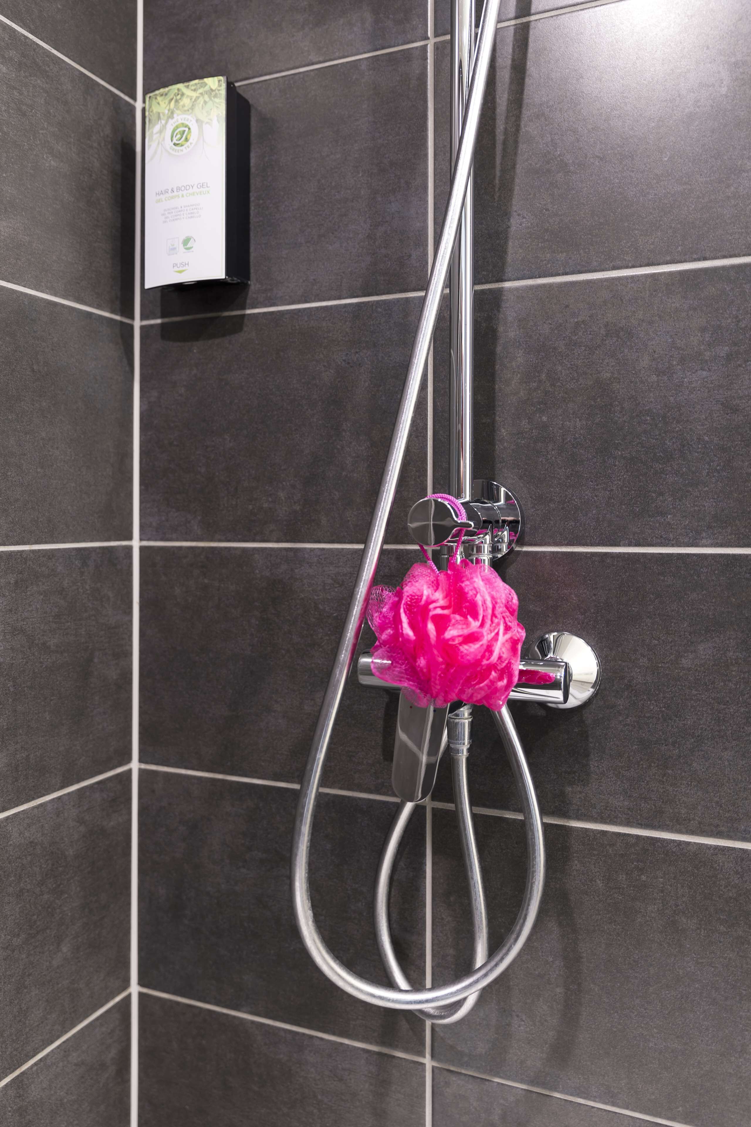 A shower with a chrome hose and a pink scrubber.