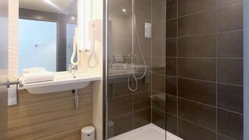 Une salle de bain moderne avec une douche à parois de verre, un lavabo avec un miroir et des toilettes.