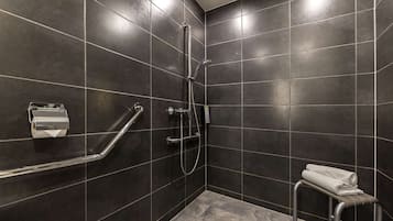 A modern bathroom with dark tiles, a shower, a toilet, and a towel rack.
