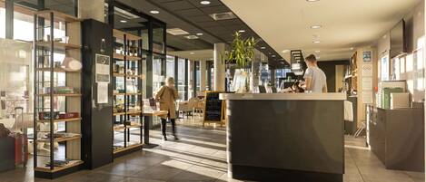 A modern interior with a reception desk, glass display cases, and a seating area.