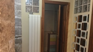 Un pasillo con un radiador blanco, una puerta de madera y suelo de baldosas.