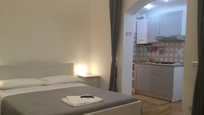 Un dormitorio con cama, mesita de noche y una cama bien hecha con una camisa blanca doblada.