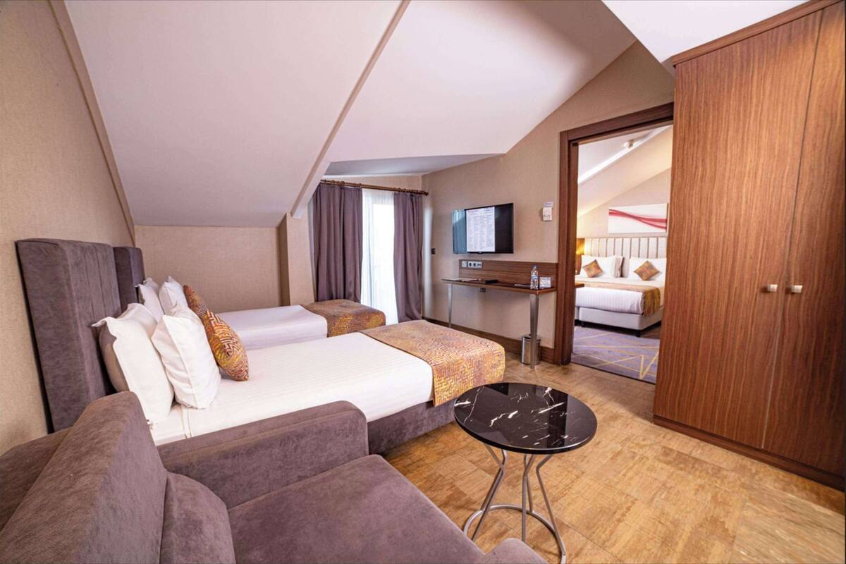 A hotel room with a bed, two sofas, a TV, and a wardrobe.