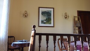 A room with a wooden chair, a table with a laptop, a framed painting, and a ladder against the wall. - Villa Anna (Osimo)