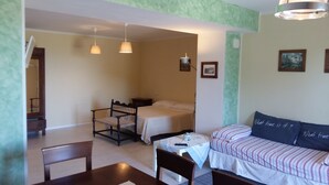 A room with a bed, a chair, a table, and a sofa. There are two hanging lights and a picture on the wall. - Villa Anna (Osimo)