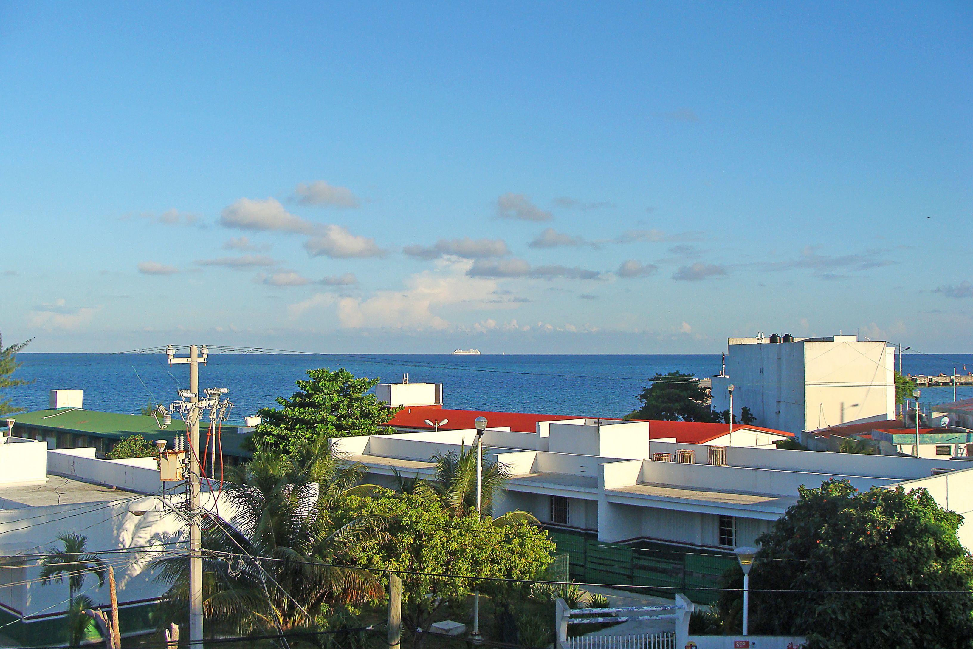 A coastal residential area with buildings, a clear sky, and the ocean in the background.