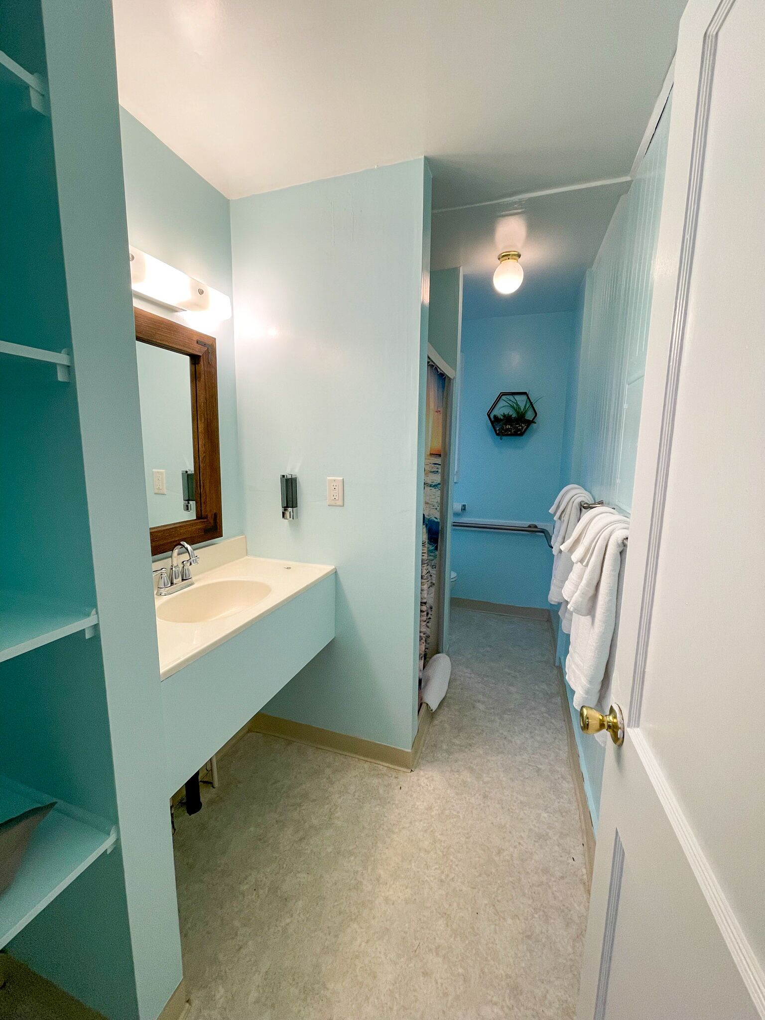 Een badkamer met een wastafel, spiegel en handdoekrek.
