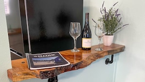 A wooden shelf with a wine bottle, two glasses, and a welcome brochure.