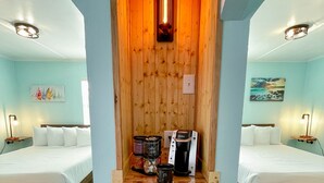 A room with two beds, a wooden shelf with a coffee maker, and a small cabinet.
