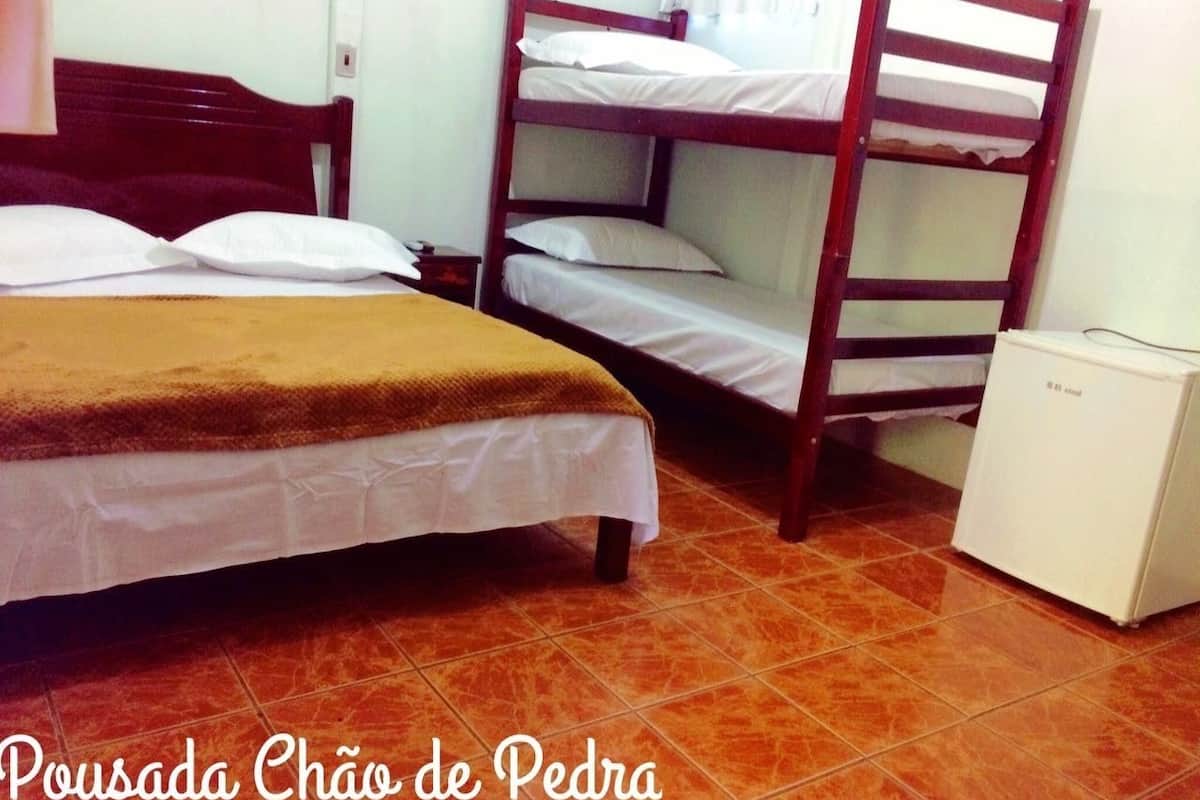 A room with a bed, a bunk bed, and a small white refrigerator.