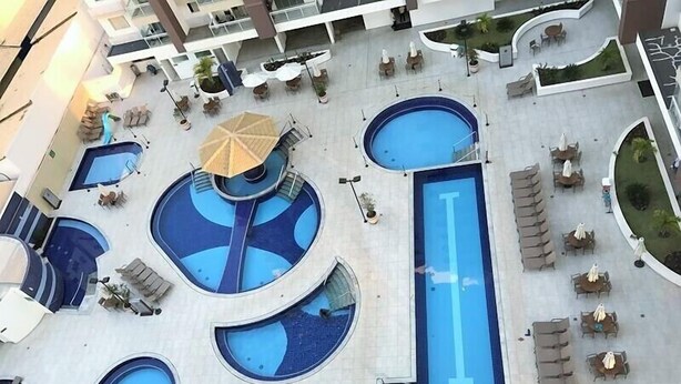 Un espace piscine sur le toit, comprenant plusieurs piscines, des chaises longues et des parasols.