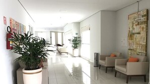 Un hall d’hôtel moderne doté d’un comptoir d’accueil, d’un espace salon et de grandes fenêtres laissant entrer la lumière naturelle.