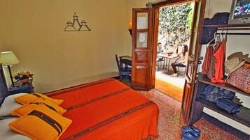 A hotel room with a bed, a chair, a table, and a wardrobe.