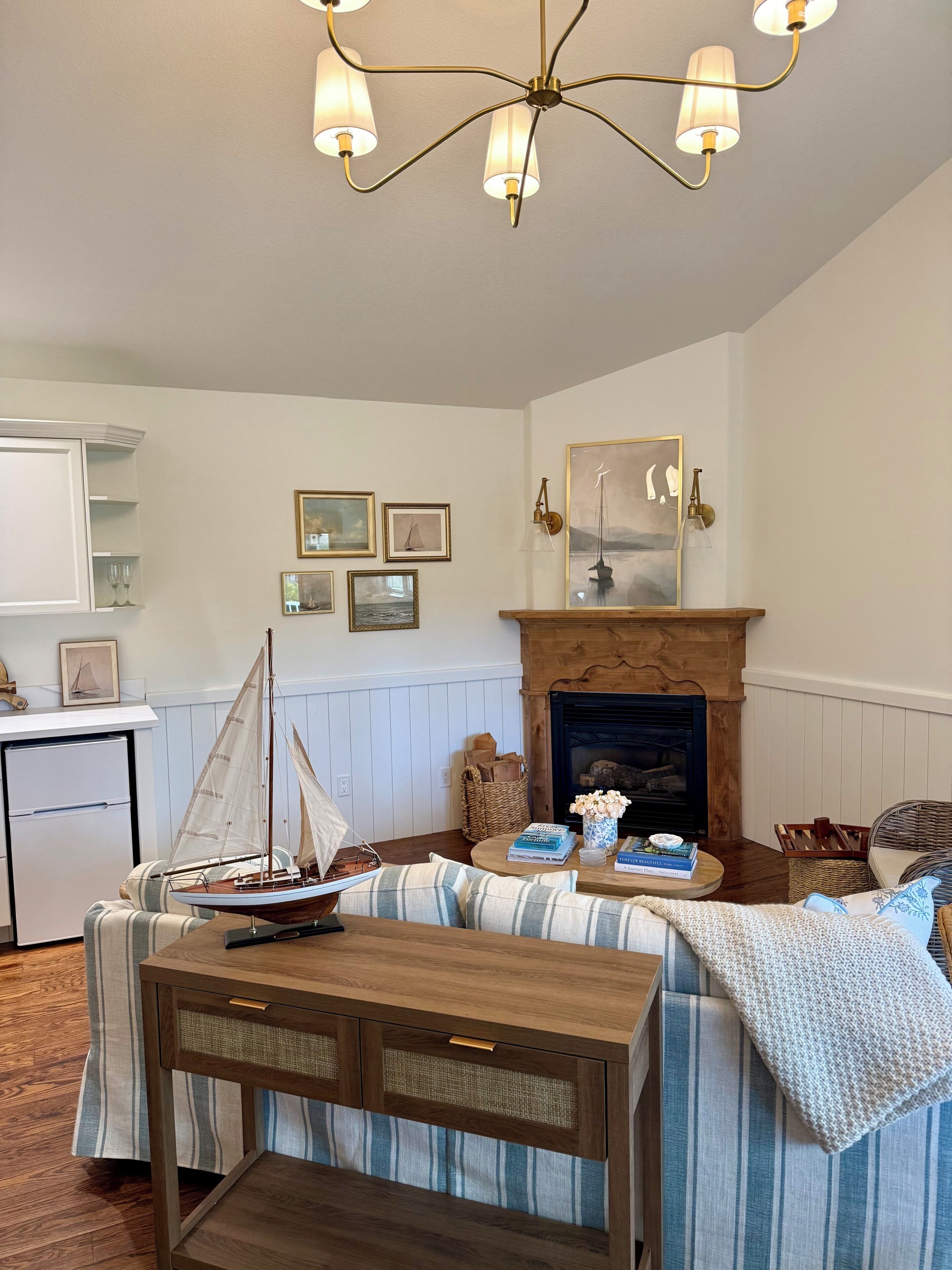 A cozy living room with a fireplace, a dining table, and a small sailboat model.