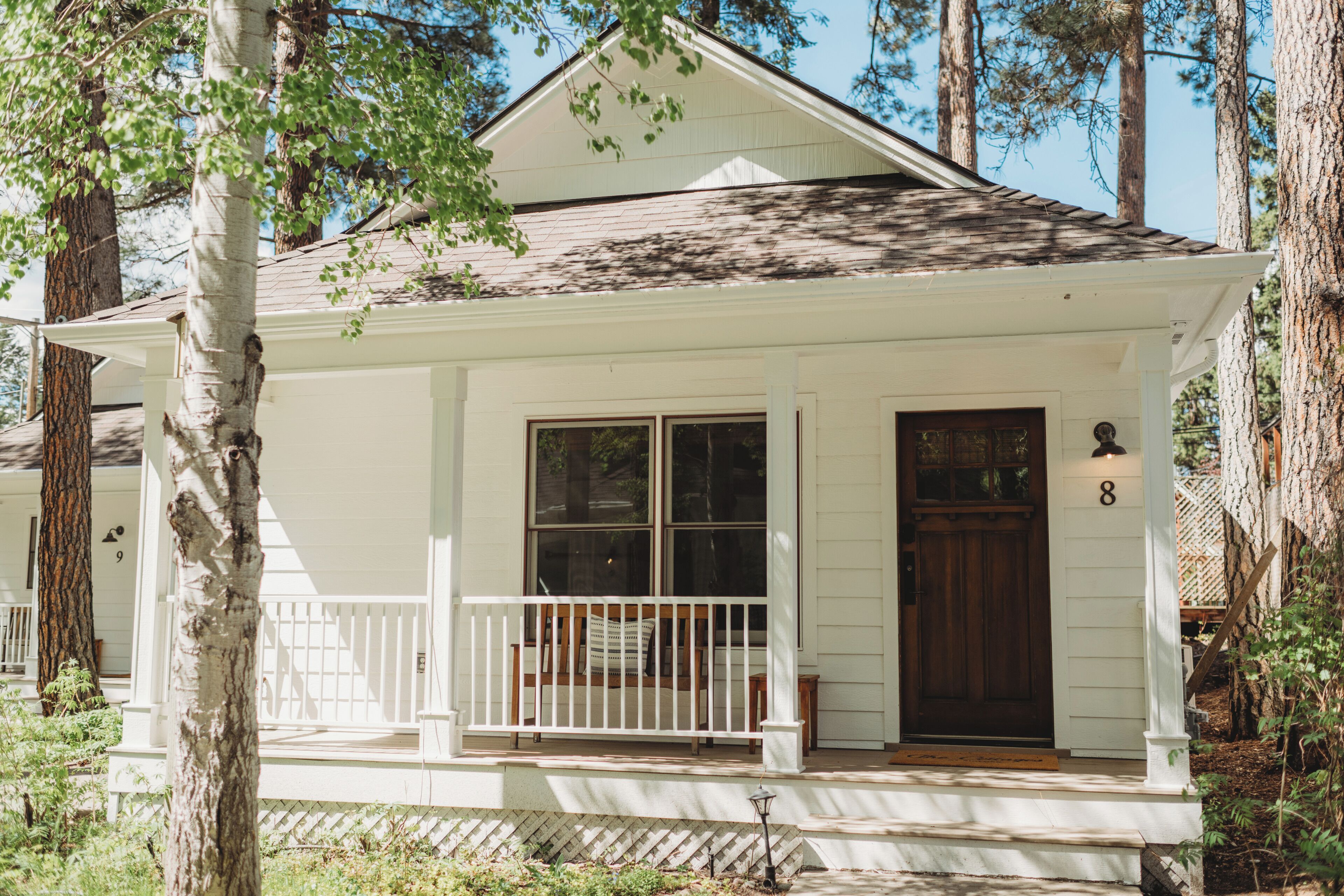 A white single-story house with a porch, a front door, and a mailbox.