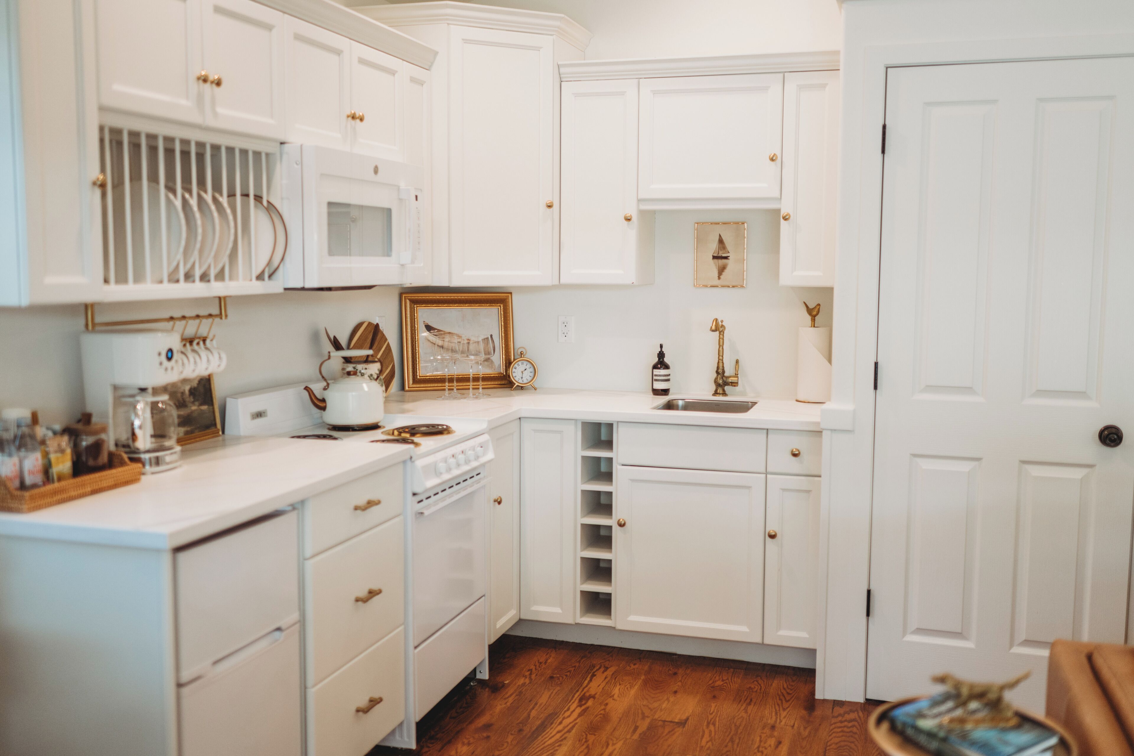 Une cuisine avec des meubles blancs, un plan de travail en bois, une cuisinière et un évier.