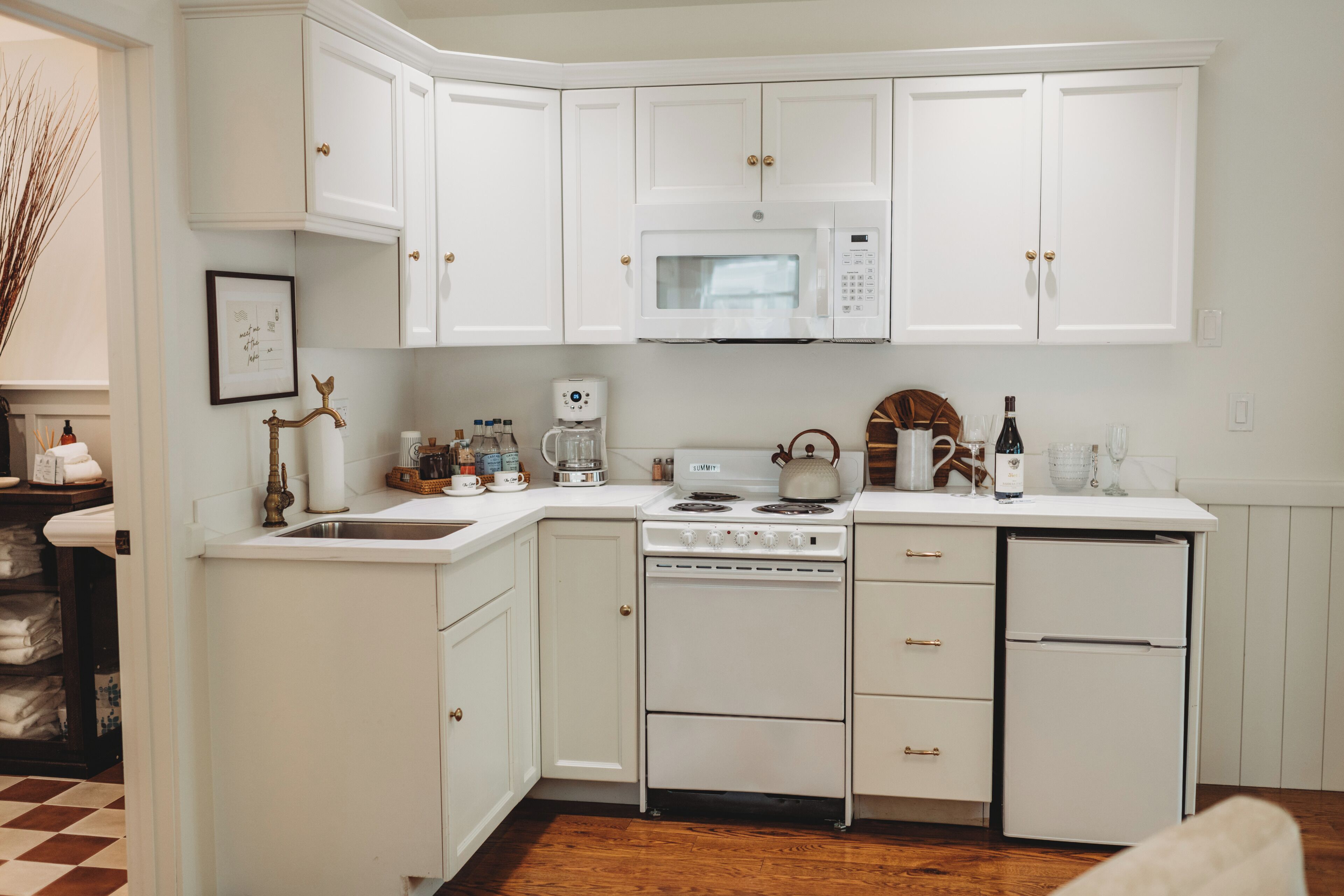 A kitchen with white cabinets, a microwave, a stove, and a refrigerator.