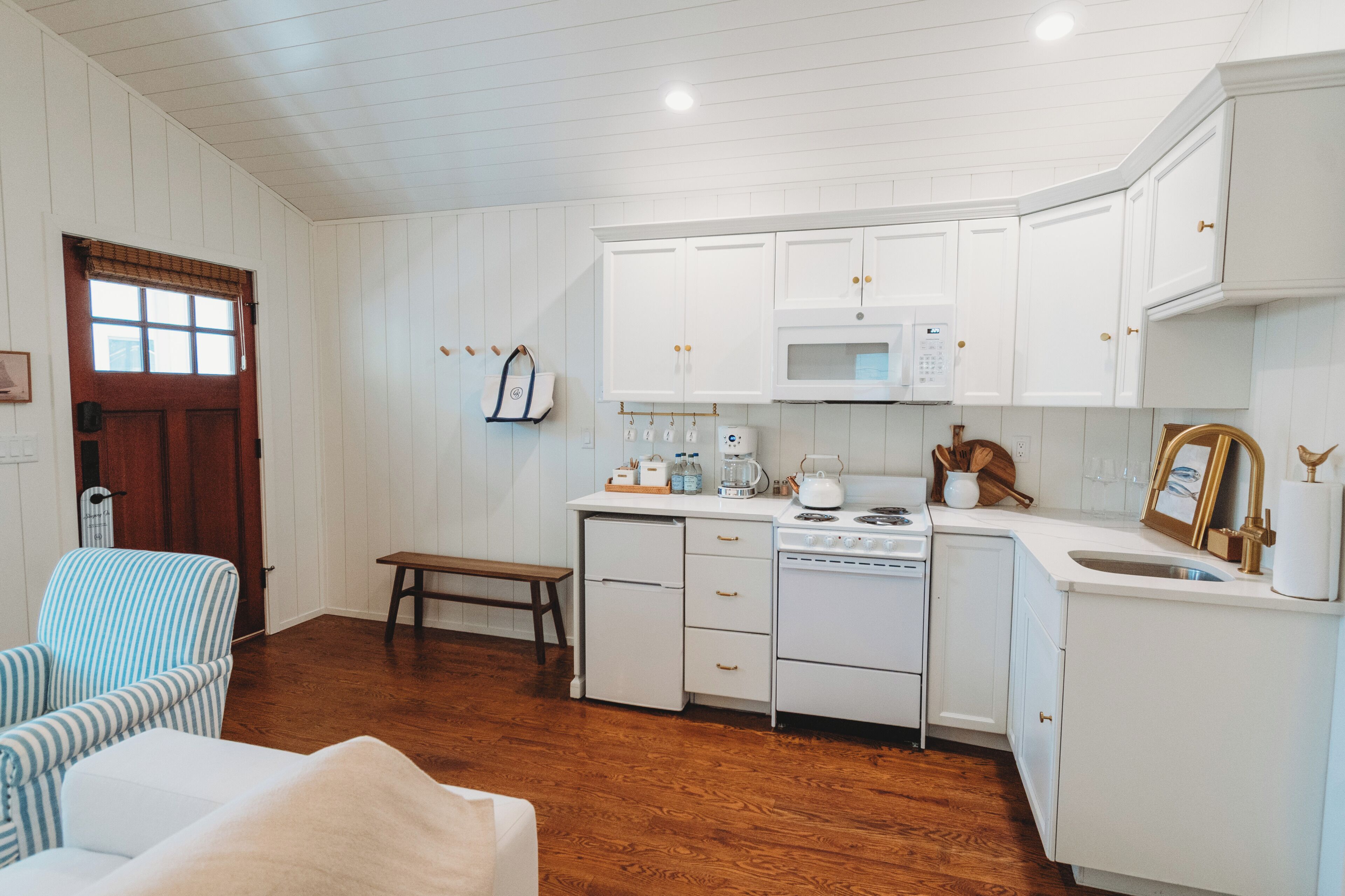 A kitchen with white cabinets, a microwave, stove, and a sink.