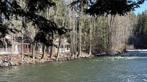 A river with a wooden dock and cabins along the shore. - The Cottages at Bigfork (Bigfork)