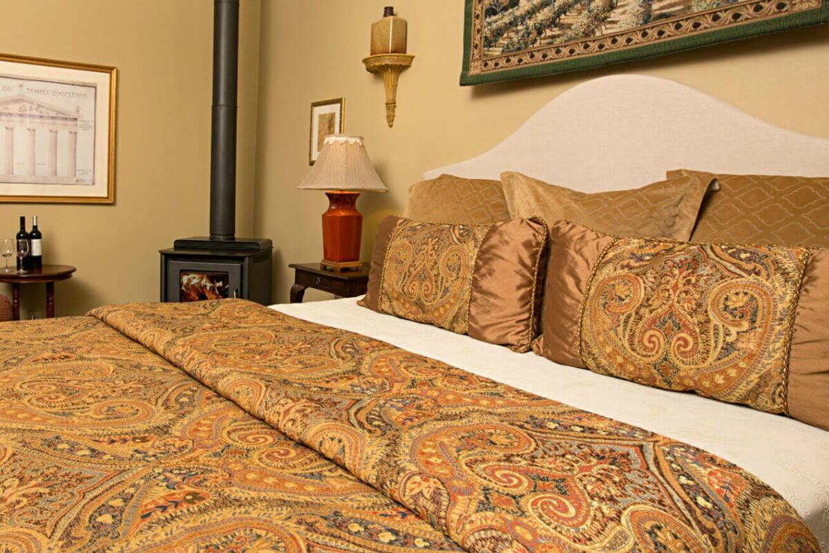 A hotel room with a large bed, a chair, a small table with a lamp, and a framed picture on the wall.
