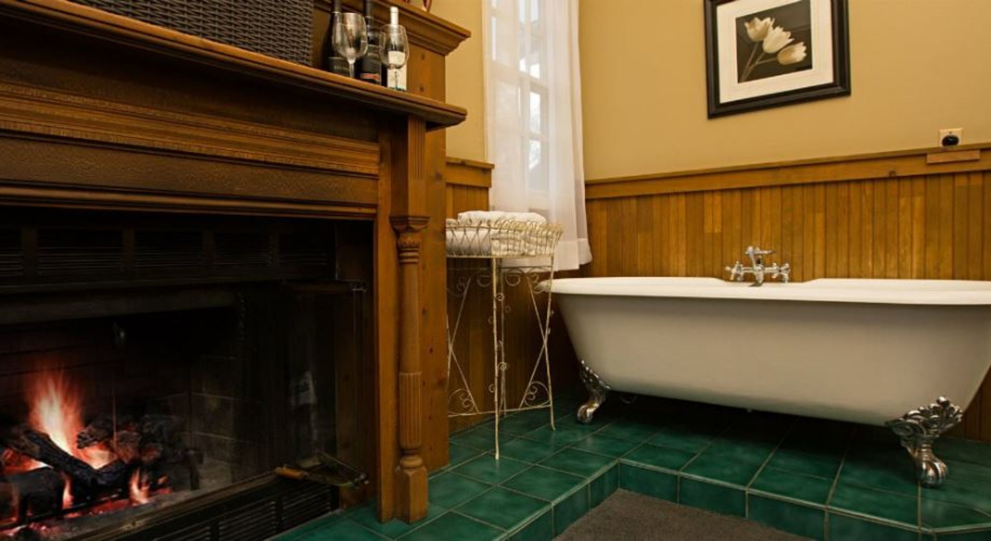 A room with a fireplace, a freestanding bathtub, and a framed picture on the wall.