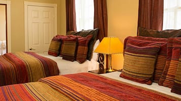 Una habitación de hotel con cama, varias almohadas, una lámpara y una puerta.