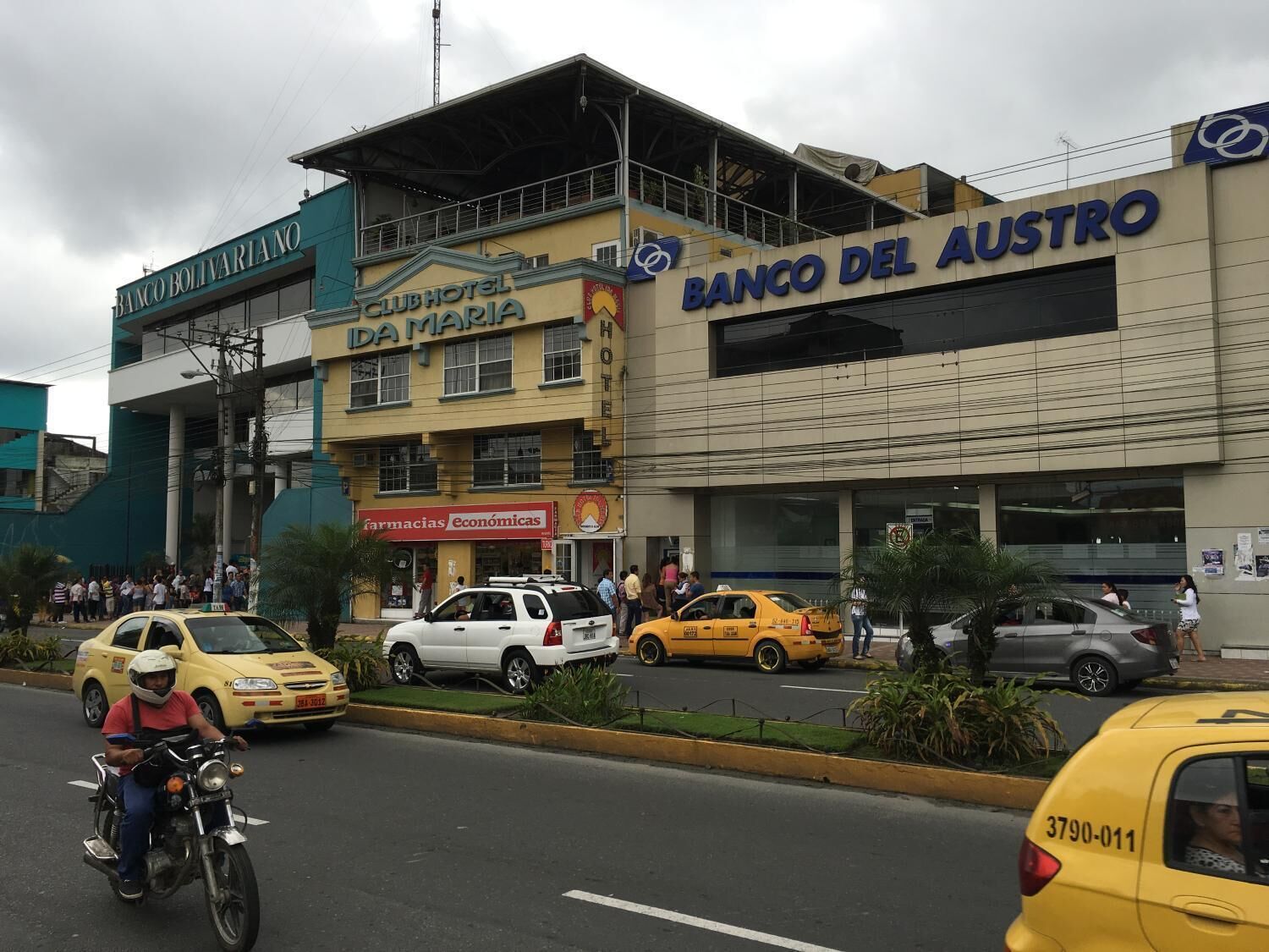 A street view with Club Maria Hotel, Banco del Austro, and a pharmacy.