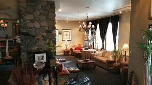 A cozy living room with a stone fireplace, comfortable seating, and a bookshelf.