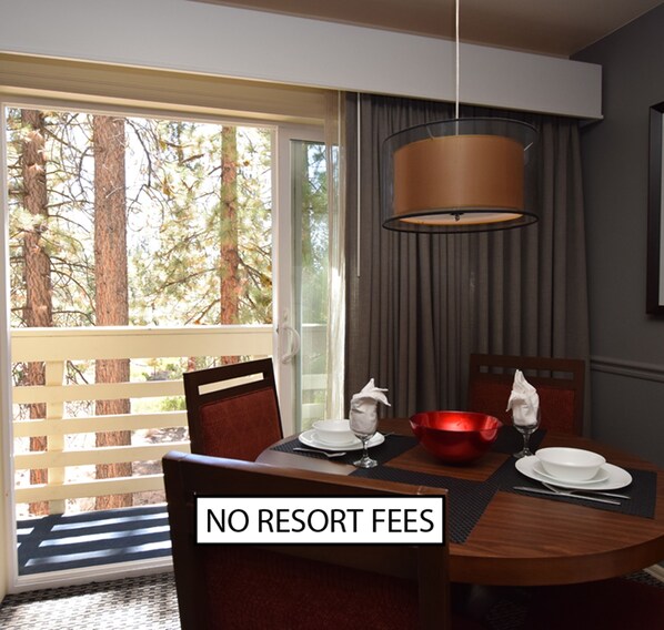 A dining area with a table set for two, a red bowl, and a hanging light fixture. - The Lodge at Kingsbury Crossing (Stateline)