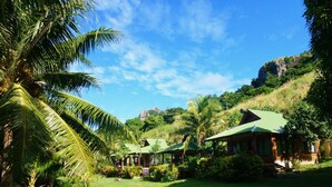 A tropical resort with multiple green-roofed cottages surrounded by lush greenery and palm trees. - Naqalia Lodge (Wayasewa Island)