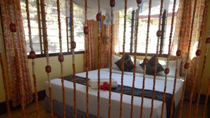A hotel room with a bed, curtains, and a window. - Naqalia Lodge (Wayasewa Island)