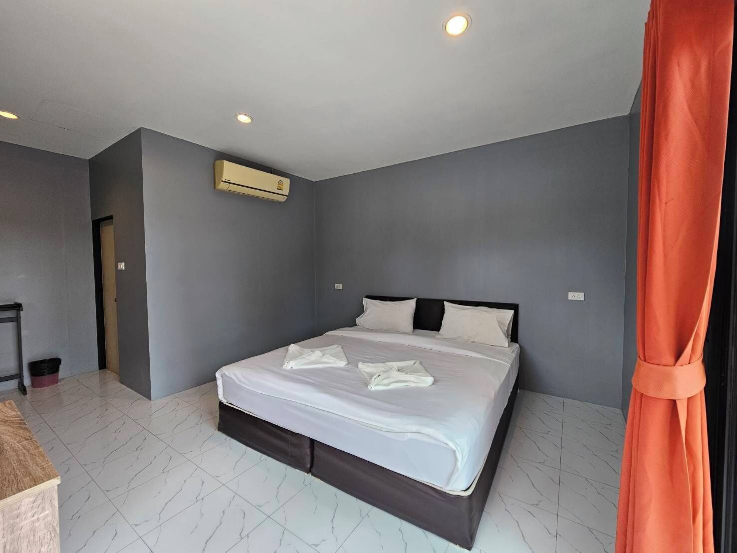 A modern hotel room with a large bed, grey walls, and a marble floor.