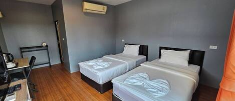 Una camera d'albergo con due letti, una scrivania con una sedia e un condizionatore d'aria.