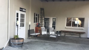 A covered outdoor area with a concrete floor, a bench, a ladder, and a potted plant.
