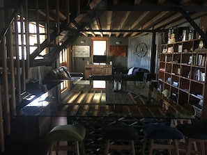 A rustic interior with a glass table, leather sofas, a bookshelf, and a staircase. - The Workshops Clyde Accommodation (Clyde)