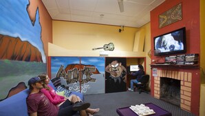 Ein Zimmer mit Fernseher, Kamin und Wandgemälde.