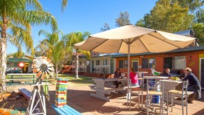 Eine Terrasse im Freien mit Picknicktischen, einer Windmühle und einem Gebäude mit einem gelben Schild.