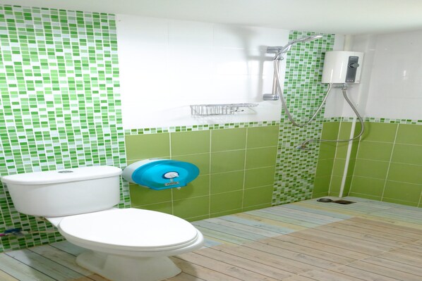 A bathroom with a toilet, a shower, and a green-tiled wall. - Banmai Hom Resort (Pluak Daeng)